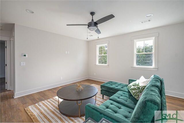 living room with a ceiling fan, visible vents, baseboards, and wood finished floors