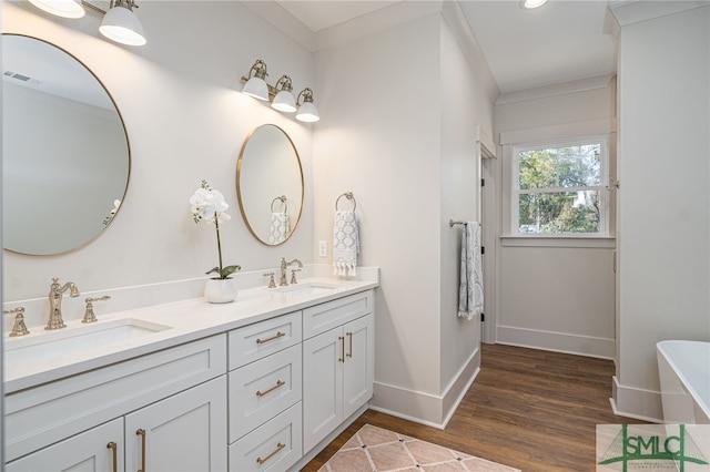 full bathroom with wood finished floors, a sink, visible vents, and crown molding