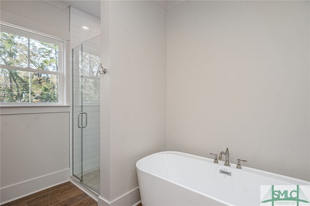 bathroom with a stall shower, a soaking tub, and wood finished floors