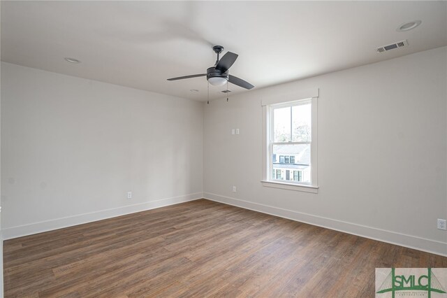 empty room featuring a ceiling fan, wood finished floors, visible vents, and baseboards