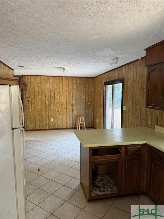 kitchen with white refrigerator, light tile patterned floors, a textured ceiling, and kitchen peninsula