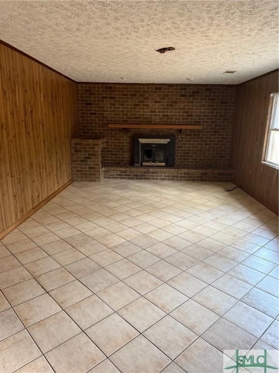 unfurnished living room with brick wall, wooden walls, and a textured ceiling