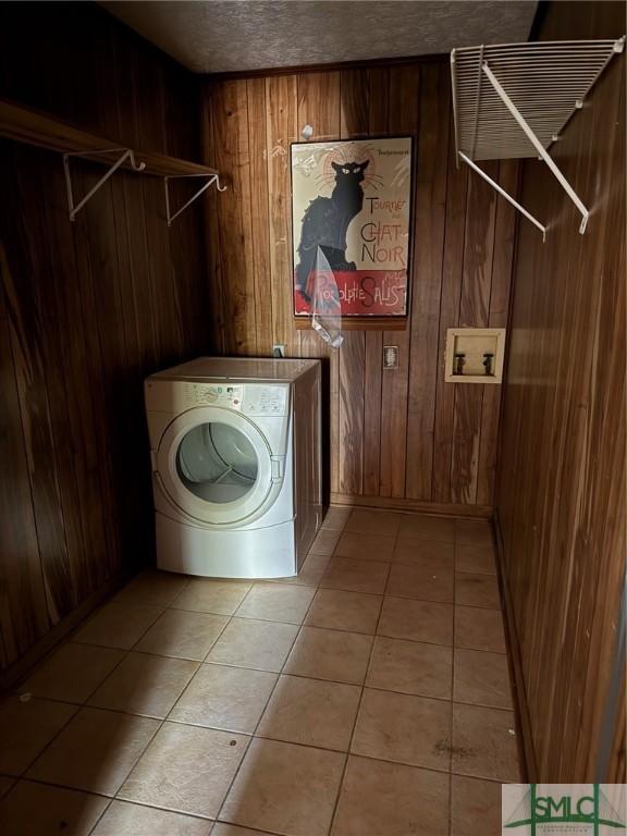 laundry area with washer / clothes dryer, light tile patterned floors, and wood walls