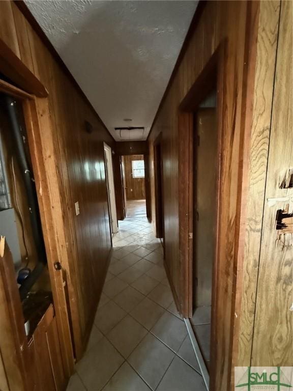 hallway featuring light tile patterned flooring and wood walls