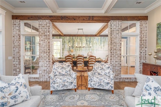 living room featuring hardwood / wood-style flooring, ornamental molding, decorative columns, and beamed ceiling