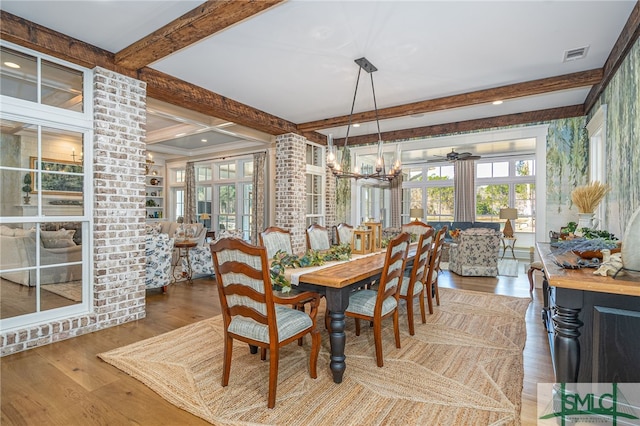 dining room with wood-type flooring, plenty of natural light, an inviting chandelier, and beam ceiling