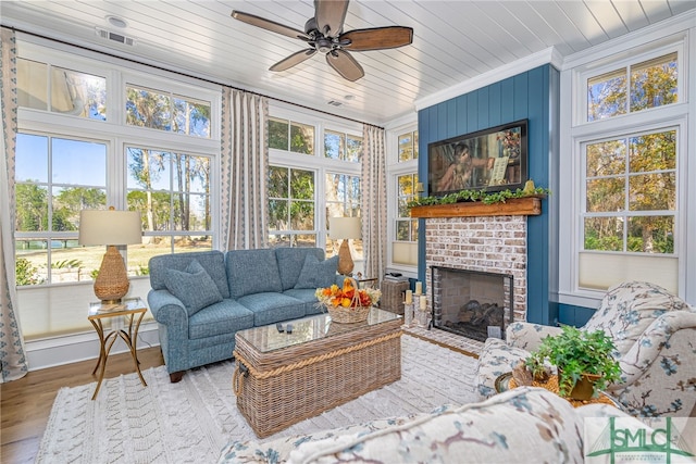 sunroom featuring ceiling fan, wood ceiling, a fireplace, and a wealth of natural light