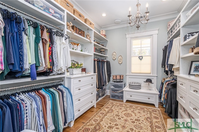 spacious closet with light hardwood / wood-style flooring and a notable chandelier