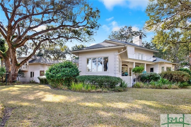 view of front of property featuring a balcony and a front lawn