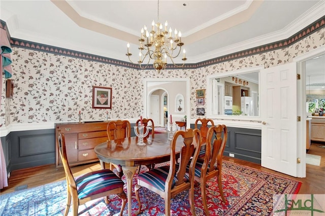 dining space featuring an inviting chandelier, hardwood / wood-style flooring, ornamental molding, and a raised ceiling