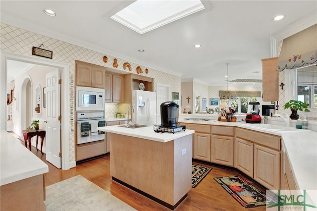 kitchen with light brown cabinetry, a center island, light hardwood / wood-style floors, crown molding, and white appliances