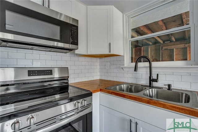 kitchen featuring tasteful backsplash, sink, stainless steel appliances, and white cabinets