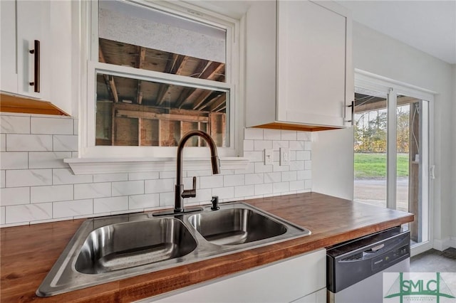 kitchen featuring tasteful backsplash, white cabinetry, dishwasher, sink, and butcher block counters