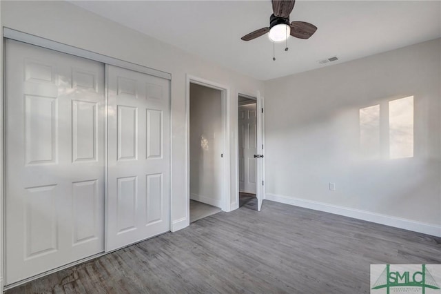 unfurnished bedroom with ceiling fan, wood-type flooring, and a closet