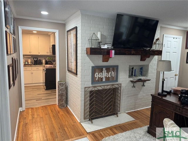 living room featuring crown molding, a fireplace, and light wood-type flooring