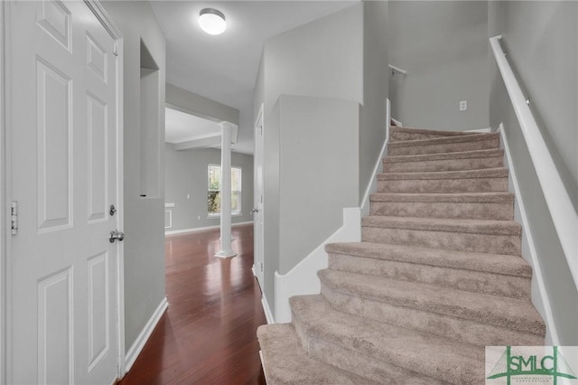 stairway with beam ceiling, hardwood / wood-style floors, and decorative columns