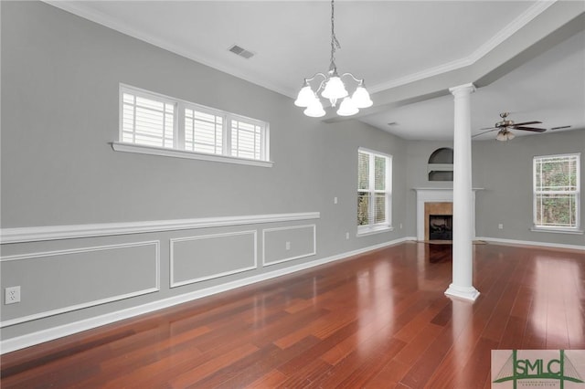 unfurnished living room featuring dark wood-type flooring, plenty of natural light, crown molding, and ornate columns