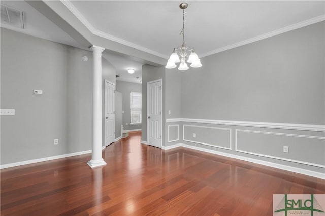 unfurnished dining area featuring ornate columns, wood-type flooring, a chandelier, and crown molding