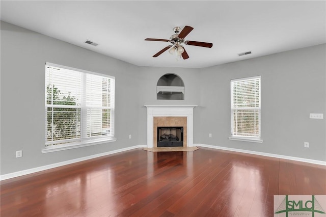 unfurnished living room with hardwood / wood-style flooring, ceiling fan, and a tiled fireplace