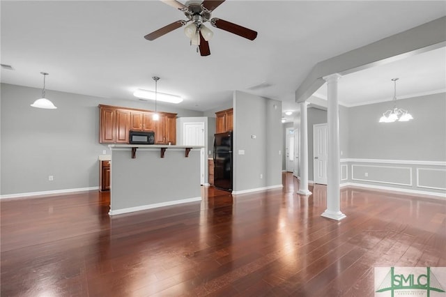 unfurnished living room with ceiling fan with notable chandelier, dark wood-type flooring, and decorative columns