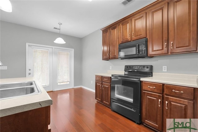 kitchen featuring pendant lighting, dark hardwood / wood-style floors, sink, and black appliances