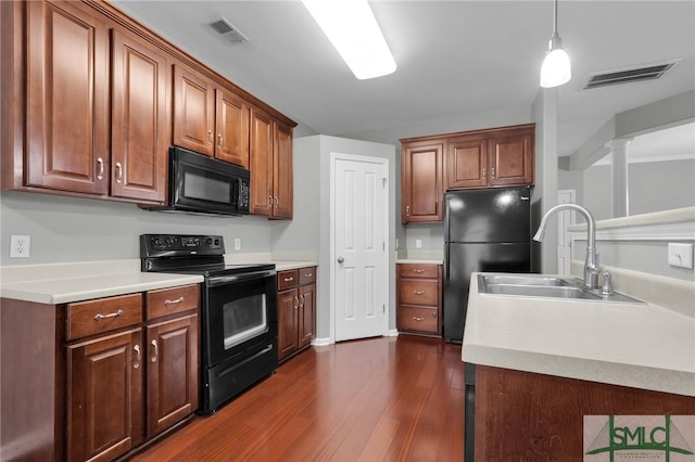 kitchen featuring sink, decorative light fixtures, dark wood-type flooring, and black appliances