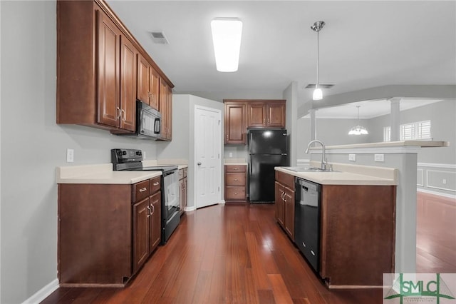 kitchen with pendant lighting, sink, dark wood-type flooring, black appliances, and ornate columns