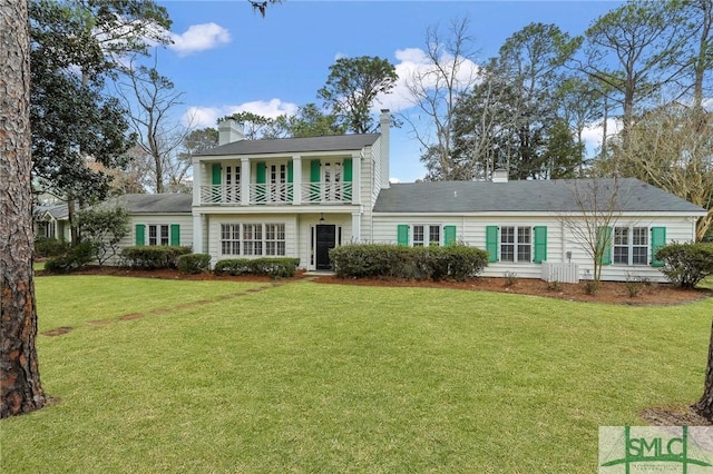 colonial home with a balcony and a front lawn