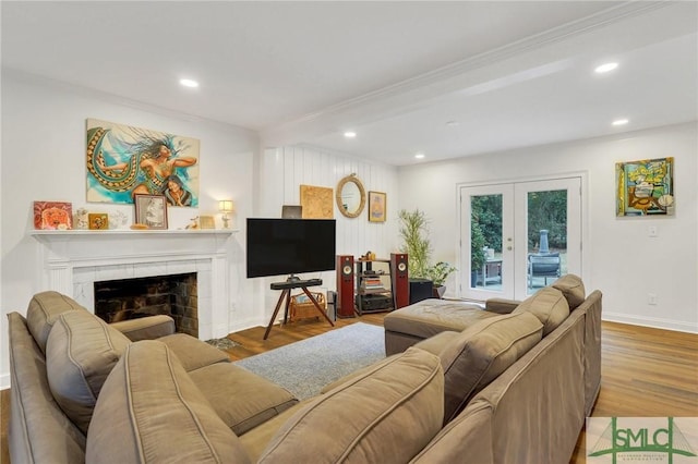 living room with french doors, a tiled fireplace, and light hardwood / wood-style flooring