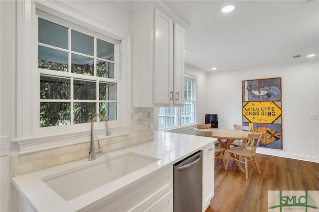 kitchen featuring sink, wood-type flooring, stainless steel dishwasher, and white cabinets