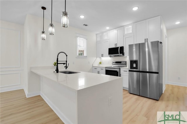 kitchen featuring white cabinetry, stainless steel appliances, sink, and pendant lighting