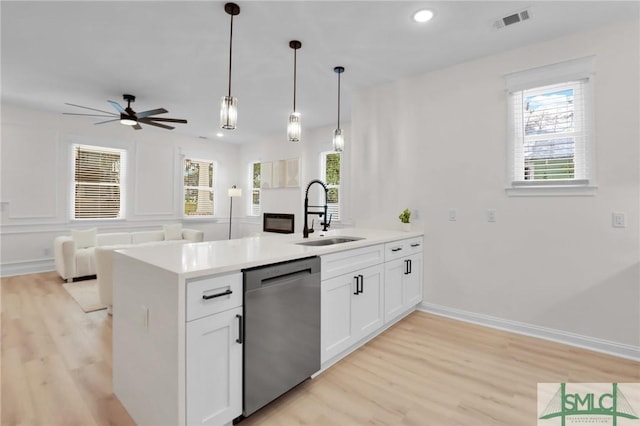 kitchen with sink, white cabinets, hanging light fixtures, stainless steel dishwasher, and kitchen peninsula