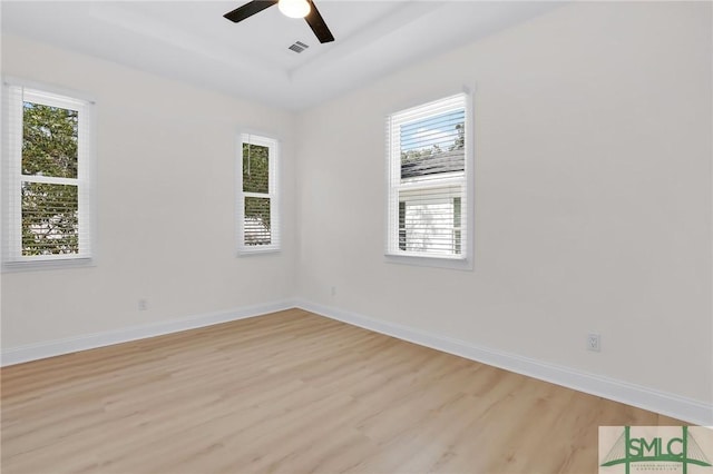 unfurnished room with a tray ceiling, light hardwood / wood-style floors, and ceiling fan