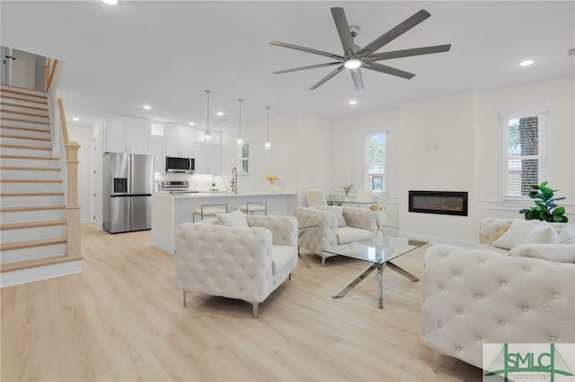 living room with sink, light hardwood / wood-style flooring, ceiling fan, and plenty of natural light