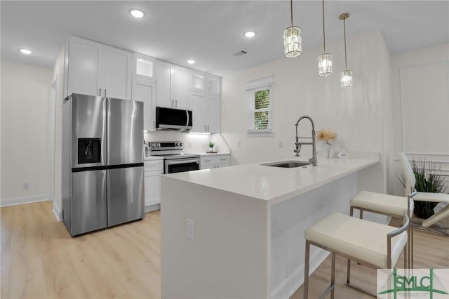 kitchen featuring stainless steel appliances, kitchen peninsula, sink, and white cabinets