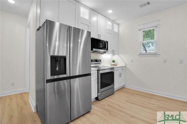 kitchen with appliances with stainless steel finishes, light hardwood / wood-style floors, and white cabinets