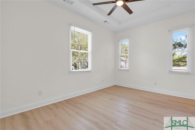 unfurnished room featuring a tray ceiling, light hardwood / wood-style flooring, and ceiling fan