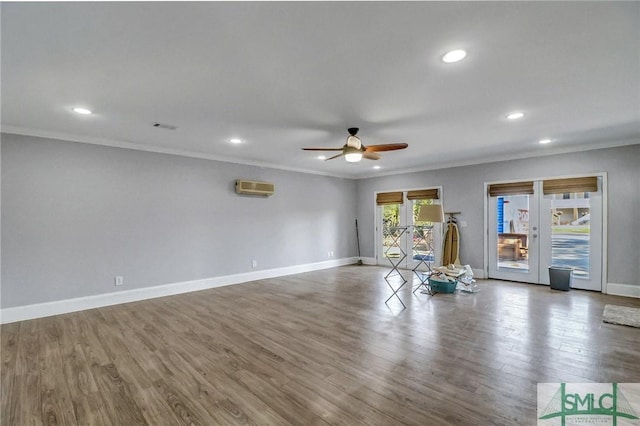 unfurnished living room featuring french doors, ornamental molding, a wall unit AC, hardwood / wood-style flooring, and ceiling fan