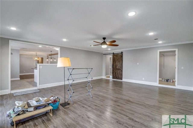 living room with crown molding, a barn door, ceiling fan, and hardwood / wood-style flooring