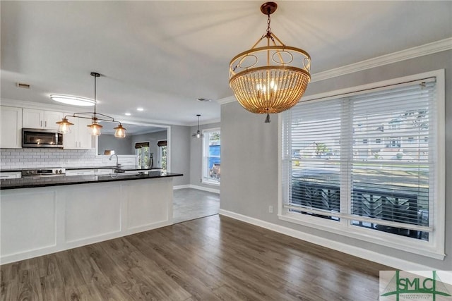 kitchen with range, tasteful backsplash, white cabinets, decorative light fixtures, and a chandelier