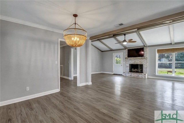 unfurnished living room with crown molding, dark wood-type flooring, vaulted ceiling with beams, a brick fireplace, and ceiling fan with notable chandelier