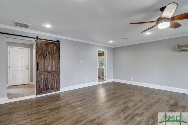 empty room featuring ceiling fan, a barn door, and dark hardwood / wood-style flooring