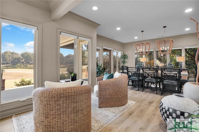 dining area with ornamental molding, an inviting chandelier, and light hardwood / wood-style flooring