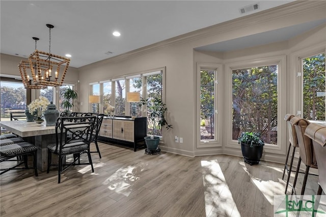 dining area with ornamental molding, a chandelier, and light hardwood / wood-style flooring