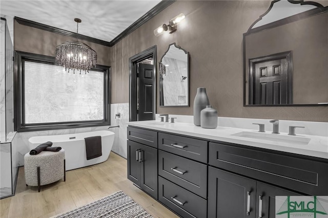 bathroom with vanity, crown molding, a chandelier, and a bathing tub