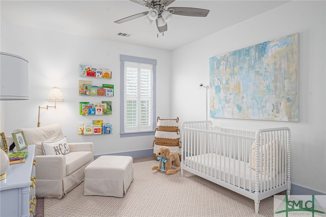 carpeted bedroom featuring a crib and ceiling fan