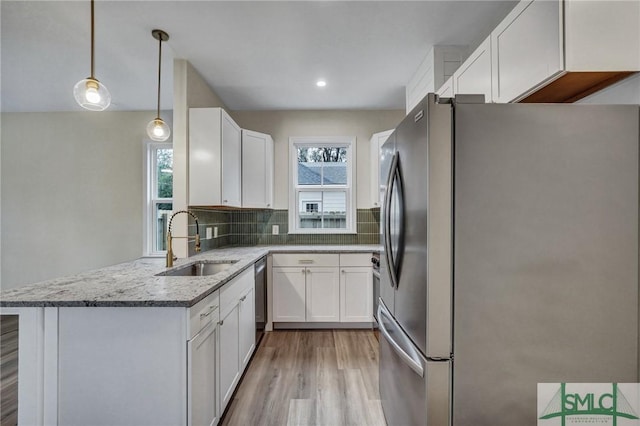 kitchen featuring sink, appliances with stainless steel finishes, white cabinetry, decorative light fixtures, and kitchen peninsula