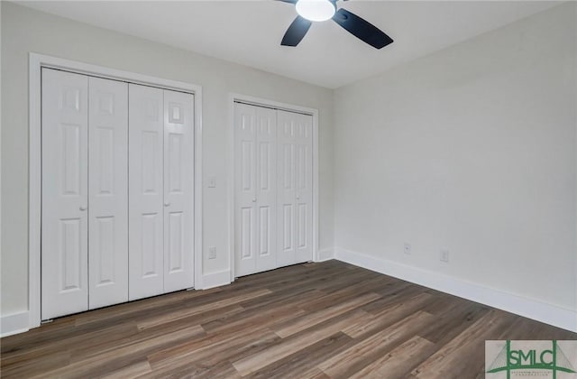 unfurnished bedroom featuring multiple closets, ceiling fan, and dark hardwood / wood-style flooring