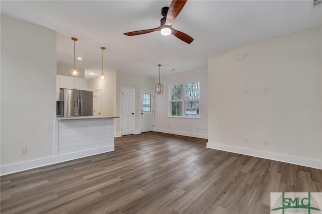 unfurnished living room featuring ceiling fan and dark hardwood / wood-style flooring