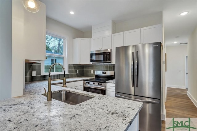 kitchen with white cabinetry, appliances with stainless steel finishes, sink, and light stone counters